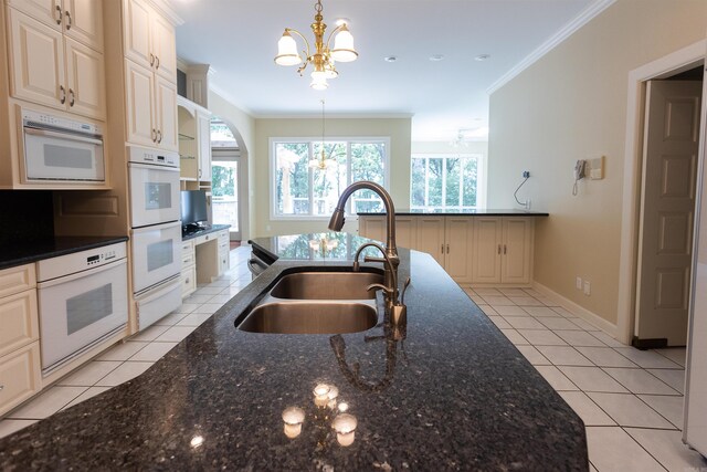 kitchen with an inviting chandelier, crown molding, a sink, and decorative light fixtures