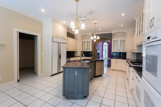 kitchen with arched walkways, light tile patterned floors, an inviting chandelier, a sink, and paneled refrigerator