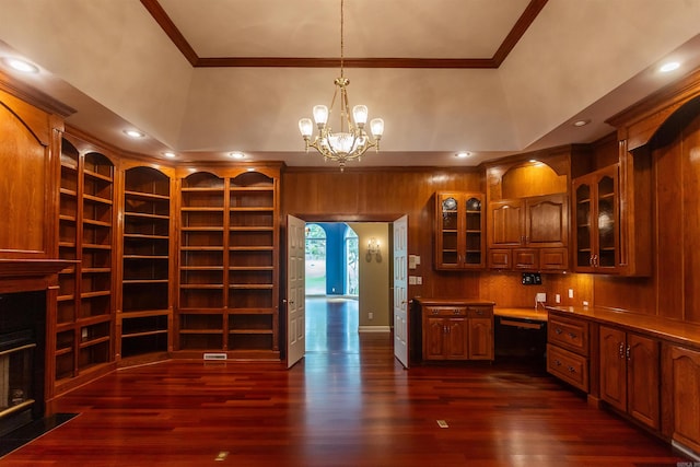 kitchen with dark wood-style floors, glass insert cabinets, brown cabinets, and built in desk