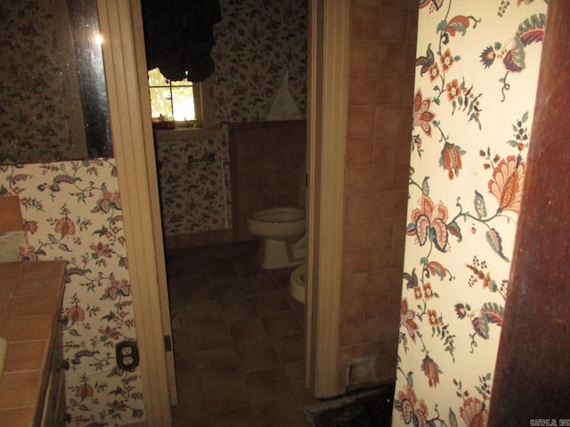 bathroom with tile patterned floors, toilet, and wallpapered walls