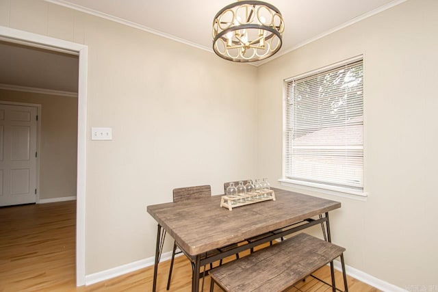 dining space featuring crown molding, light wood-type flooring, and a chandelier