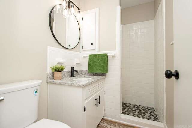 bathroom with vanity, toilet, and a tile shower