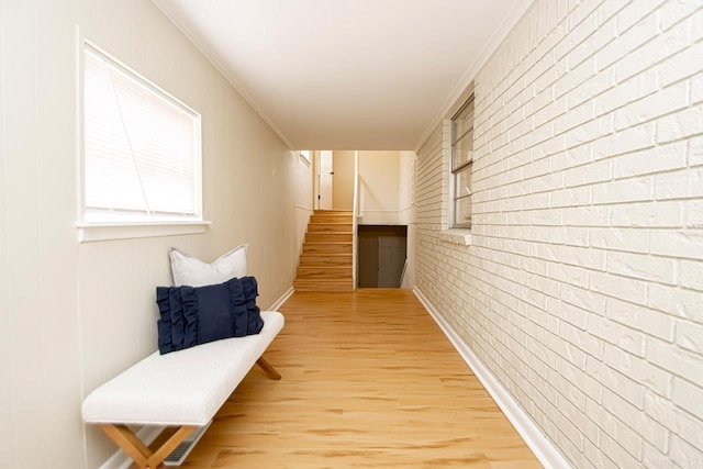 corridor featuring light hardwood / wood-style floors, brick wall, and ornamental molding