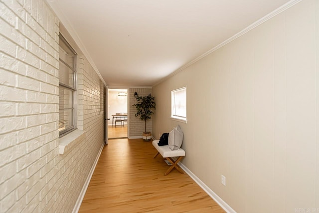 hall featuring brick wall, light wood-type flooring, and ornamental molding