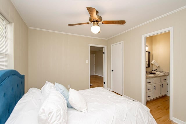 bedroom featuring ceiling fan, crown molding, light hardwood / wood-style flooring, and connected bathroom