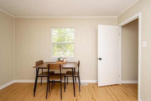 dining room with crown molding and light wood-type flooring