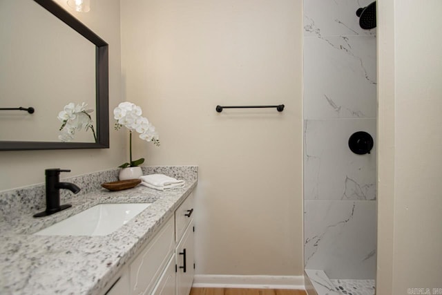 bathroom featuring vanity, a tile shower, and hardwood / wood-style flooring