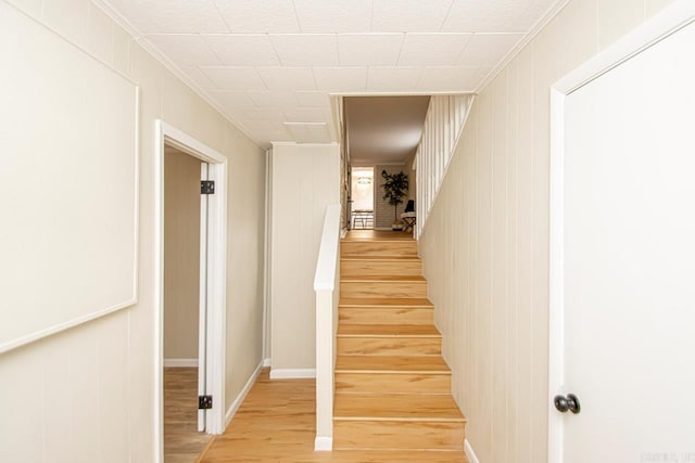 staircase with light hardwood / wood-style flooring and ornamental molding