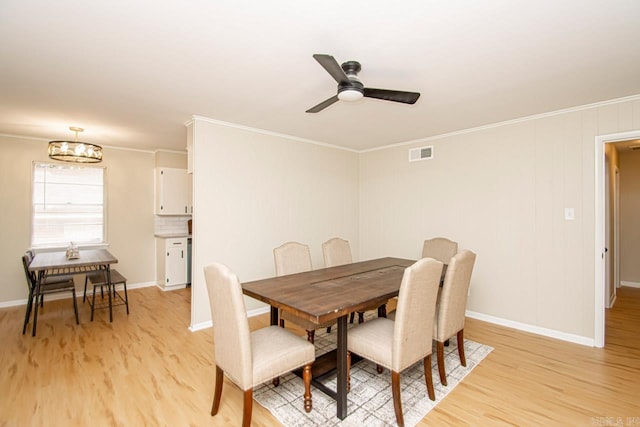 dining room with ceiling fan with notable chandelier, light hardwood / wood-style flooring, and ornamental molding