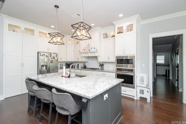 kitchen featuring appliances with stainless steel finishes, tasteful backsplash, sink, an island with sink, and dark wood-type flooring