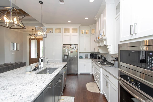 kitchen featuring white cabinets, dark wood-type flooring, stainless steel appliances, pendant lighting, and sink