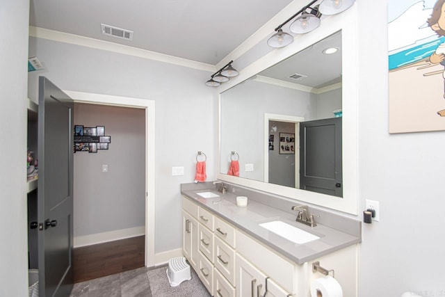 bathroom with double vanity, crown molding, and wood-type flooring