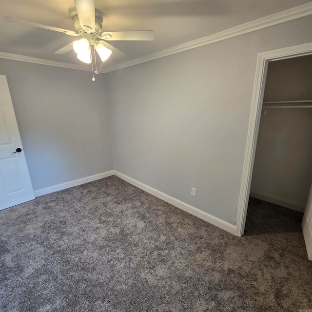 unfurnished bedroom featuring a spacious closet, a closet, crown molding, carpet flooring, and ceiling fan