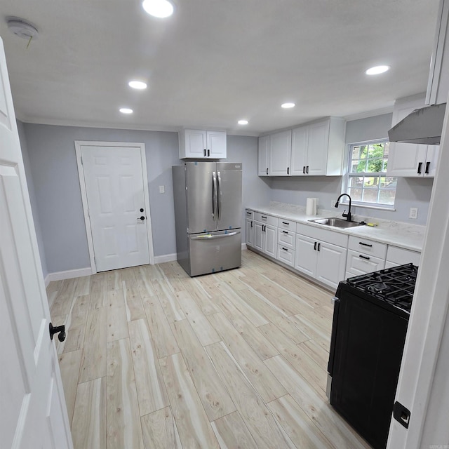 kitchen featuring stainless steel fridge, gas range oven, light hardwood / wood-style flooring, and sink