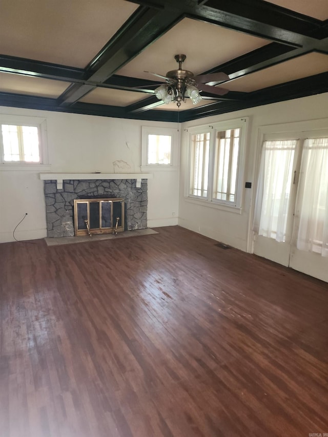 unfurnished living room with beamed ceiling, a stone fireplace, coffered ceiling, and hardwood / wood-style floors