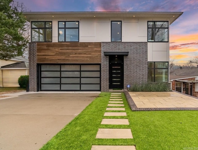 contemporary home featuring a garage and a lawn