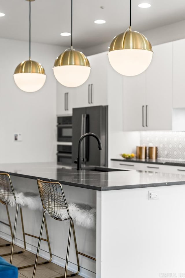 kitchen with white cabinetry, hanging light fixtures, decorative backsplash, sink, and appliances with stainless steel finishes