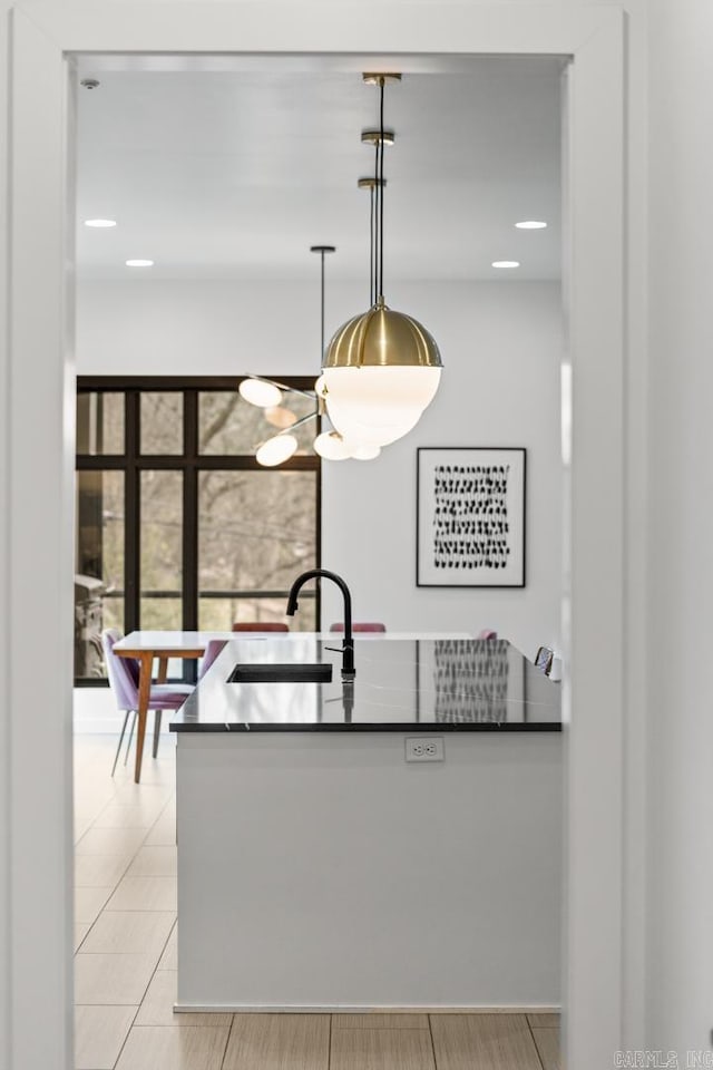 kitchen with light tile patterned flooring, sink, kitchen peninsula, and hanging light fixtures