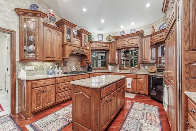 kitchen with lofted ceiling, brown cabinetry, gas stovetop, and a center island