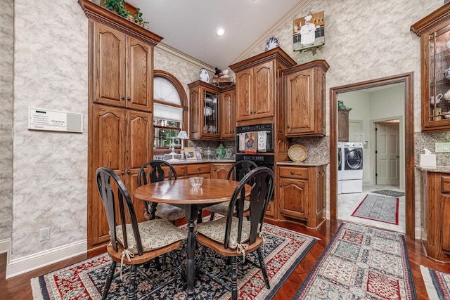 dining room featuring baseboards, dark wood finished floors, washer / dryer, lofted ceiling, and ornamental molding