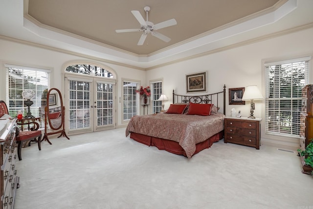 bedroom with access to exterior, a raised ceiling, french doors, and light colored carpet