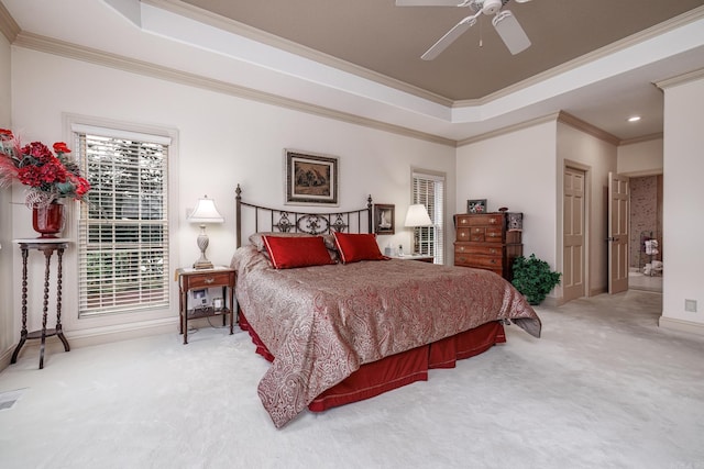 carpeted bedroom with ceiling fan, crown molding, and a tray ceiling