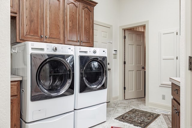 washroom featuring baseboards, cabinet space, marble finish floor, and washing machine and clothes dryer