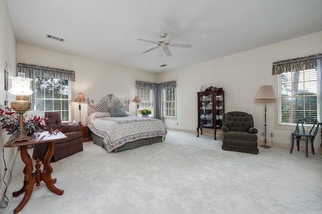 carpeted bedroom with visible vents, baseboards, and a ceiling fan