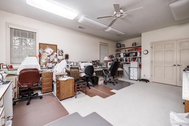 office space with visible vents, carpet floors, and a ceiling fan