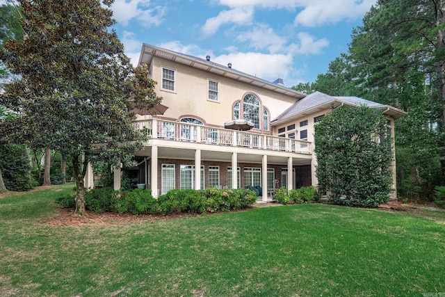 rear view of house with a lawn and stucco siding