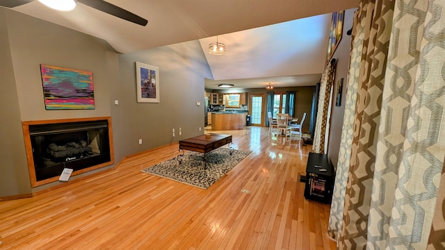 living room featuring light hardwood / wood-style flooring, lofted ceiling, and ceiling fan