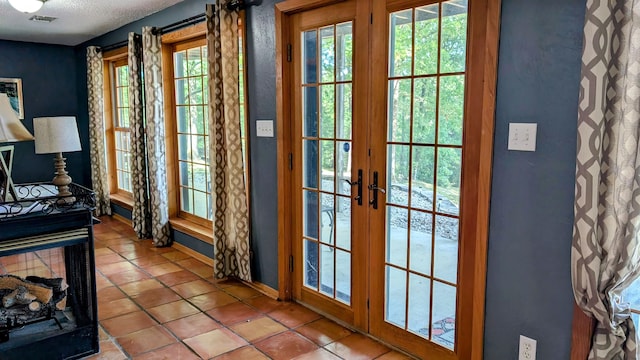 doorway featuring light tile patterned flooring, a healthy amount of sunlight, and french doors