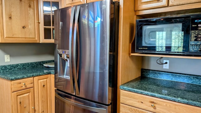 kitchen featuring dark stone counters, black microwave, and stainless steel refrigerator with ice dispenser