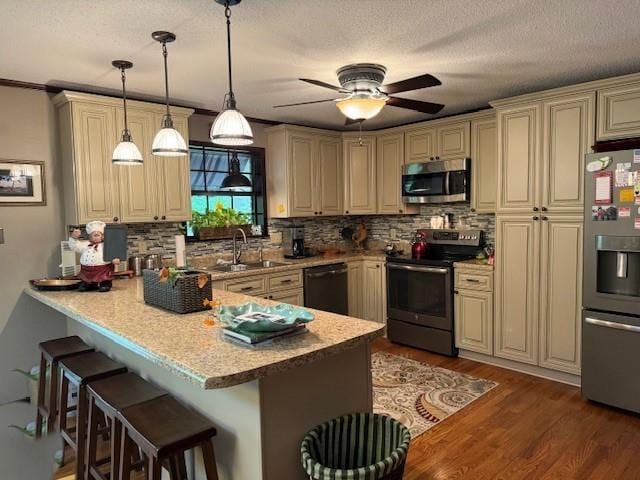 kitchen with sink, a kitchen breakfast bar, hanging light fixtures, kitchen peninsula, and stainless steel appliances