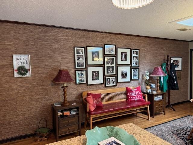 interior space featuring hardwood / wood-style flooring, ornamental molding, and a textured ceiling