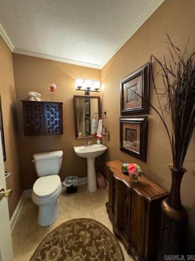 bathroom with tile patterned floors, ornamental molding, toilet, and a textured ceiling