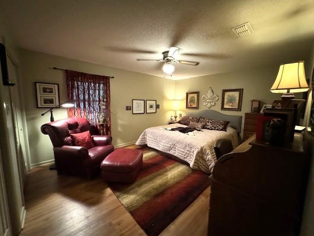 bedroom with hardwood / wood-style floors, a textured ceiling, and ceiling fan