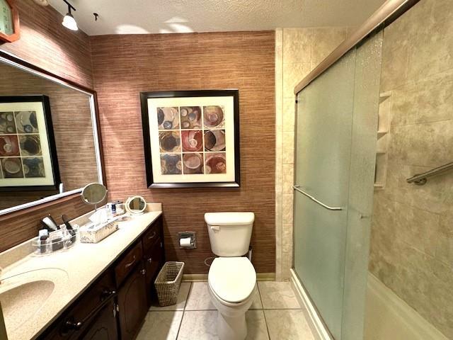 bathroom featuring vanity, an enclosed shower, toilet, tile patterned floors, and a textured ceiling