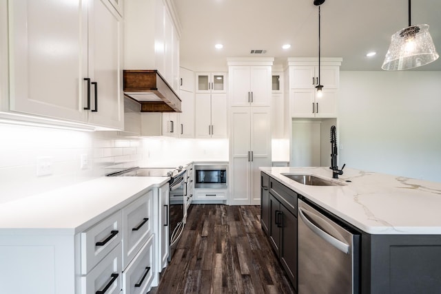 kitchen with sink, pendant lighting, stainless steel appliances, a kitchen island with sink, and white cabinets