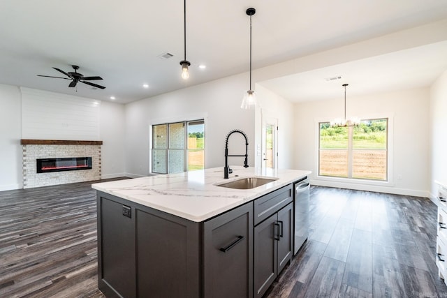 kitchen with sink, dishwasher, hanging light fixtures, dark hardwood / wood-style floors, and light stone counters