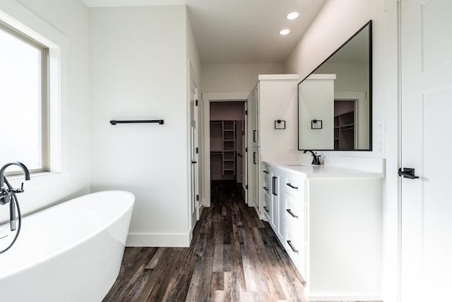 bathroom featuring wood-type flooring, vanity, and a tub