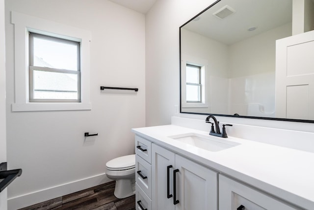 bathroom with hardwood / wood-style flooring, vanity, toilet, and walk in shower