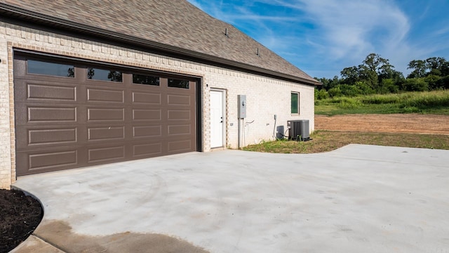 view of side of home with a garage and central AC unit