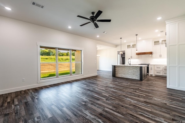 kitchen featuring hanging light fixtures, white cabinetry, a kitchen island with sink, and dark wood-type flooring