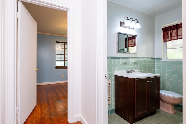 bathroom featuring vanity, ornamental molding, toilet, and tile walls
