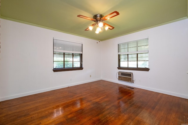 spare room with ceiling fan, a wall unit AC, visible vents, wood finished floors, and baseboards