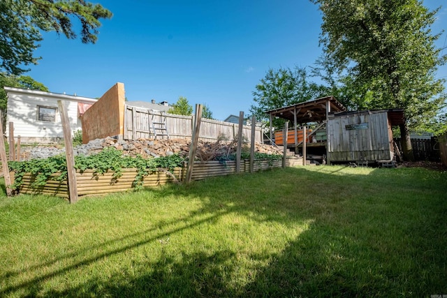 view of yard with fence, an outdoor structure, a garden, and a storage shed