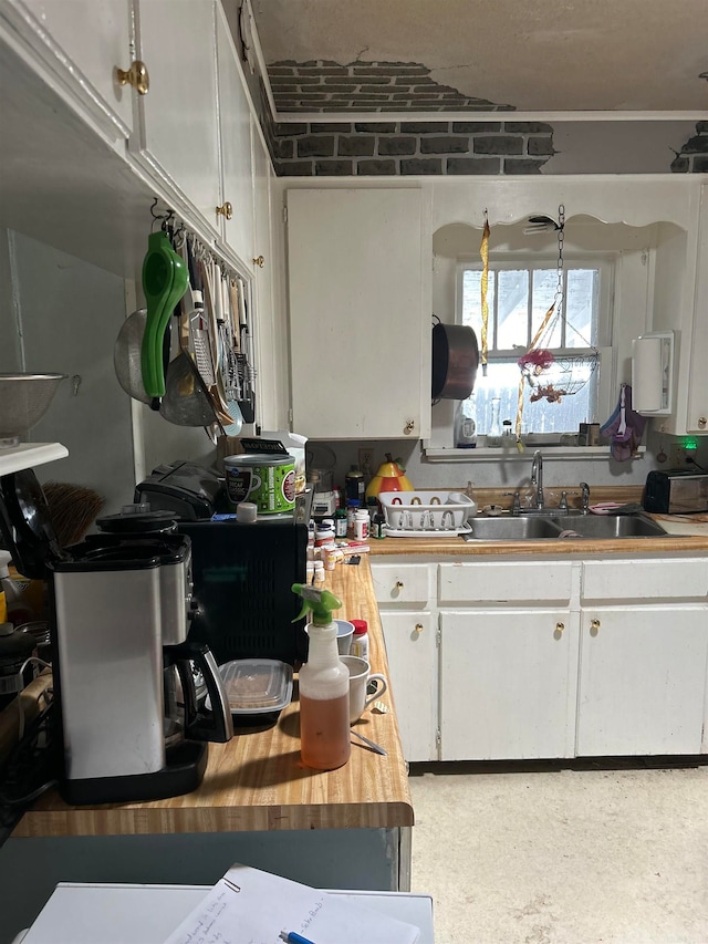 kitchen with butcher block countertops, sink, and white cabinetry