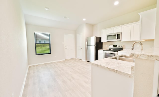 kitchen featuring stainless steel appliances, sink, light stone counters, light hardwood / wood-style floors, and white cabinetry