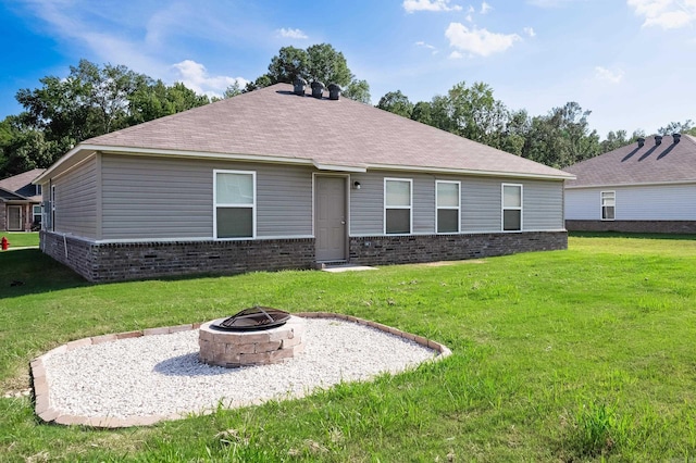 back of property featuring a yard and an outdoor fire pit